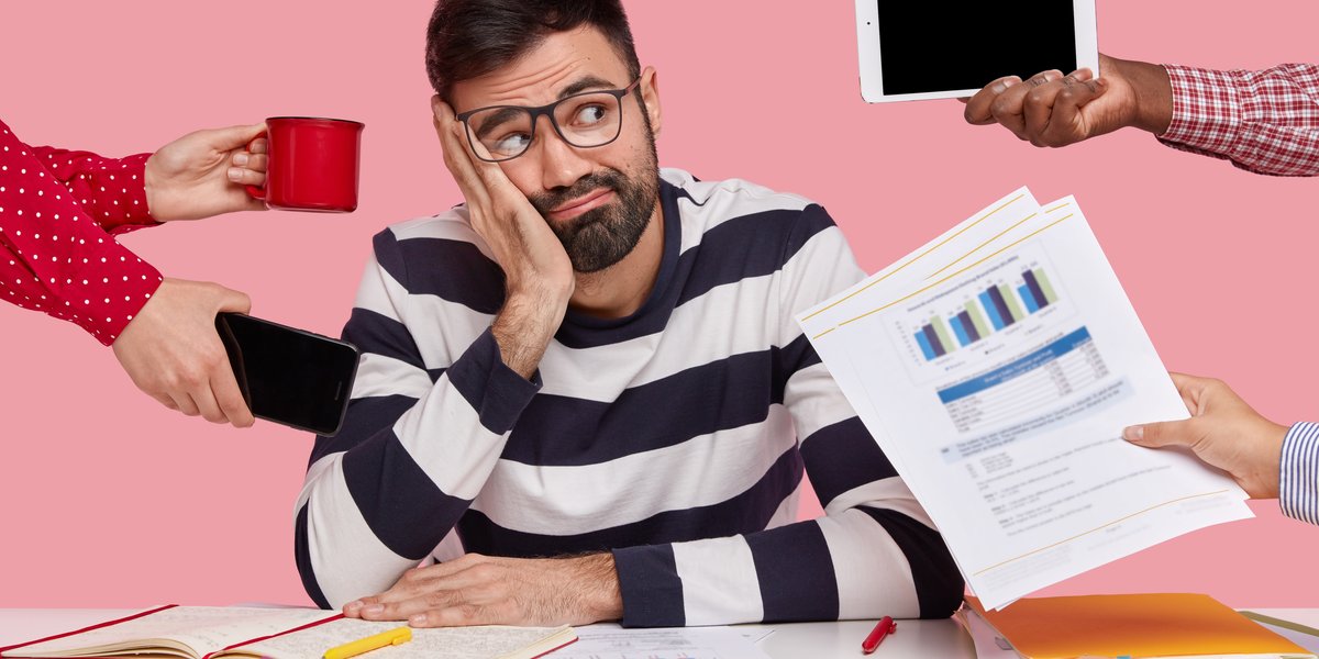 brunet-man-sitting-desk-surrounded-with-gadgets-papers