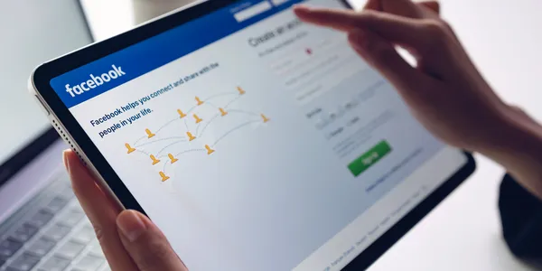 hand-is-pressing-facebook-screen-apple-ipad-pro-social-media-are-using-information-sharing-networking