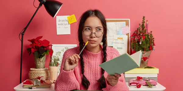 serious-contemplating-asian-girl-with-combed-plaits-holds-notebook-pencil-writes-down-future-plans-goals-coming-christmas
